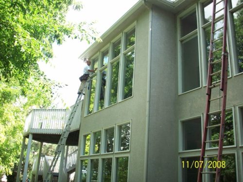 Technician from Mike's Window and Gutter Cleaning cleaning exterior second story windows on Kansas City home
