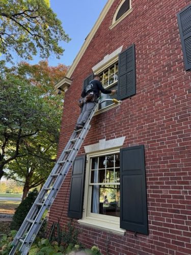 Window washer from Mike's Window and Gutter Cleaning, washing exterior second story windows on Kansas City home